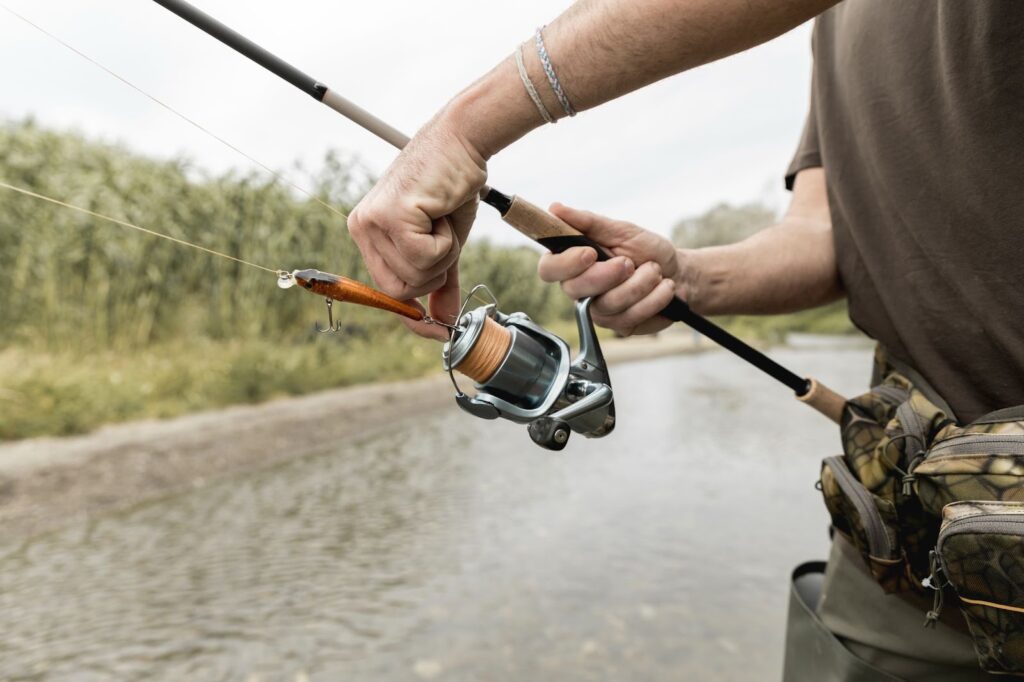 Man holding a fishing rod and reel by the water